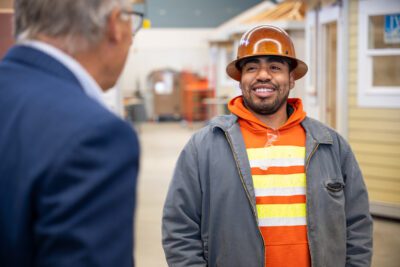 A Renton Technical College student wearing safety gear talks with a visiting politician.